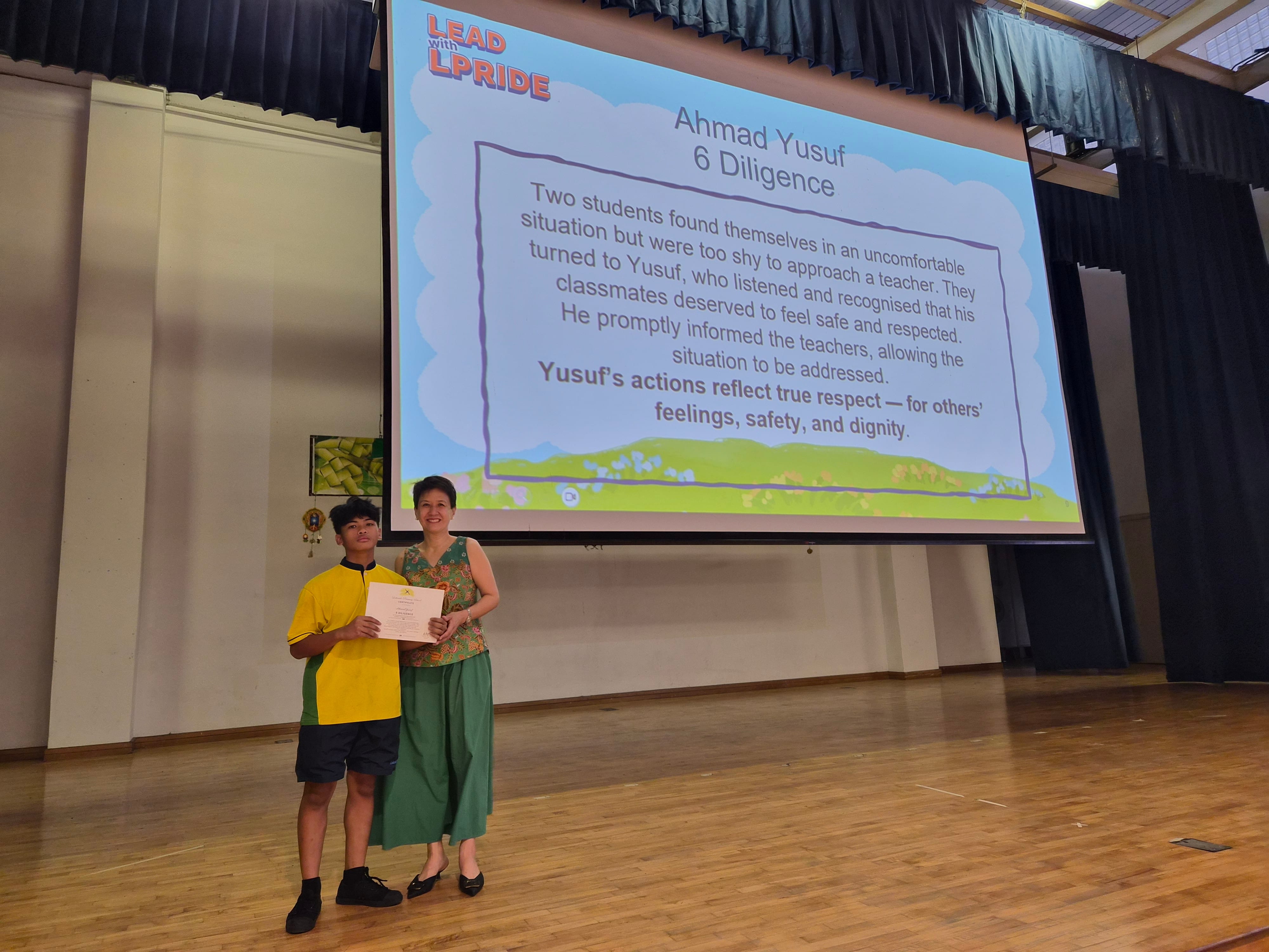 Ahmad Yusuf receiving his certificate from Mrs Liang on stage